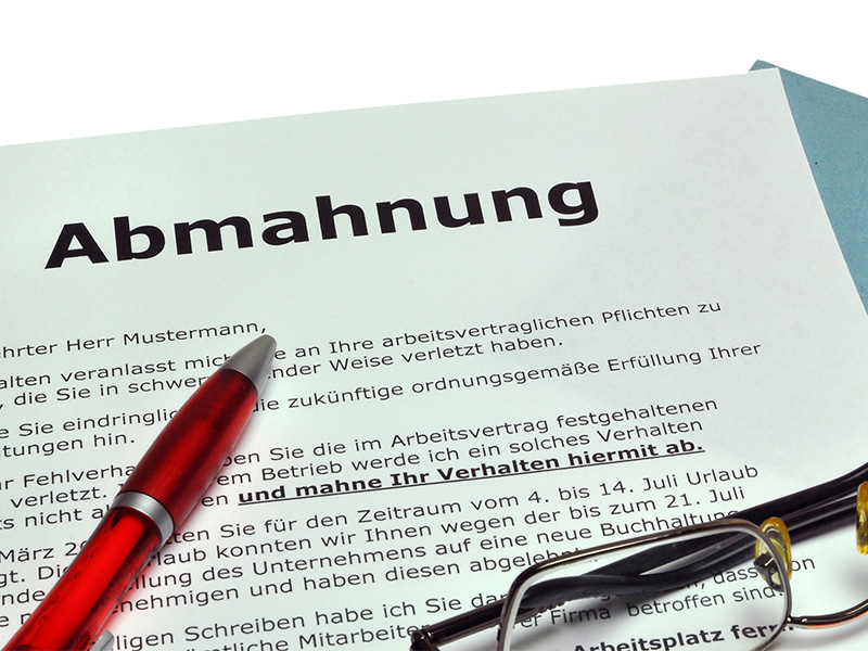 Per Post zugestellte schriftliche Abmahnung liegt geöffnet auf einem Tisch und zeigt deutlich den offiziellen Hinweis.